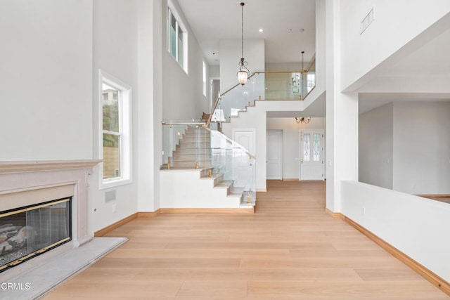 entrance foyer featuring wood finished floors, baseboards, a high ceiling, stairs, and a premium fireplace