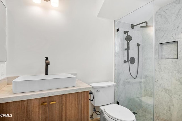 full bath with vanity, a tile shower, and toilet