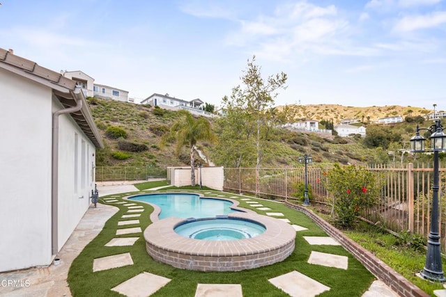 view of pool featuring a fenced backyard and a pool with connected hot tub