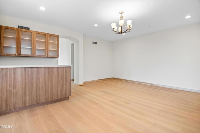 unfurnished room with light wood-style floors, arched walkways, and recessed lighting