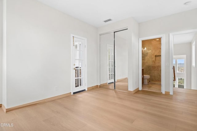 unfurnished bedroom with connected bathroom, baseboards, visible vents, and light wood-type flooring