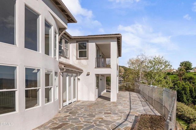 view of patio featuring fence and a balcony