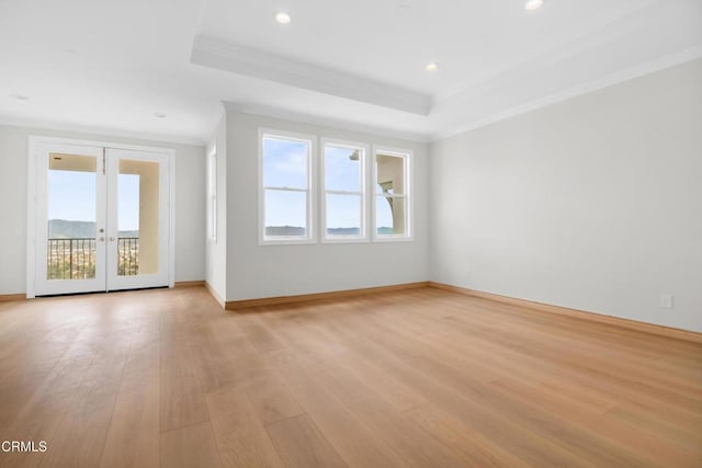 unfurnished living room featuring baseboards, ornamental molding, light wood finished floors, and a raised ceiling