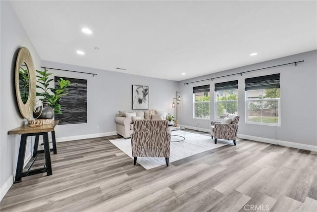 living room featuring baseboards, light wood-style flooring, and recessed lighting