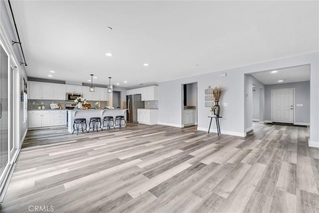 living area featuring recessed lighting, light wood-style flooring, and baseboards