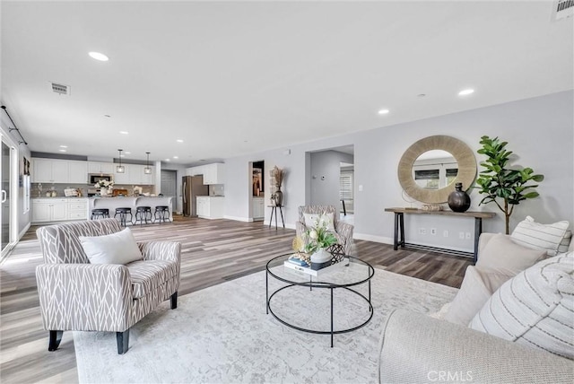living area with light wood-type flooring, recessed lighting, and baseboards