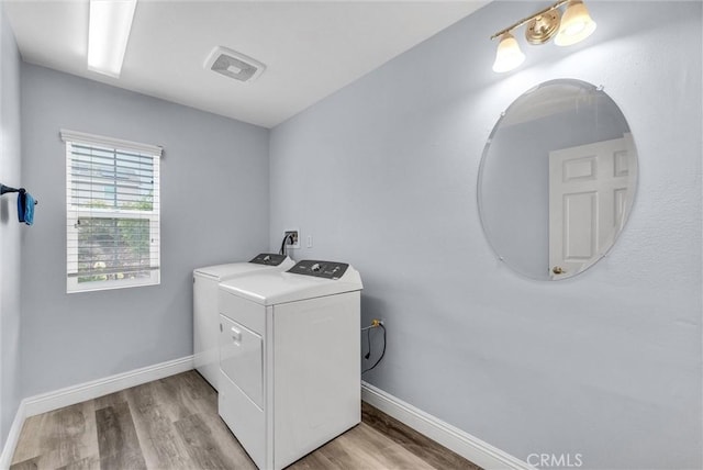 laundry area with independent washer and dryer, light wood-style flooring, and baseboards
