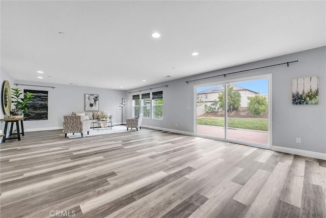 unfurnished living room featuring recessed lighting, baseboards, and light wood finished floors