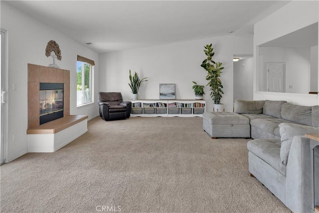 living room featuring a tiled fireplace and carpet flooring