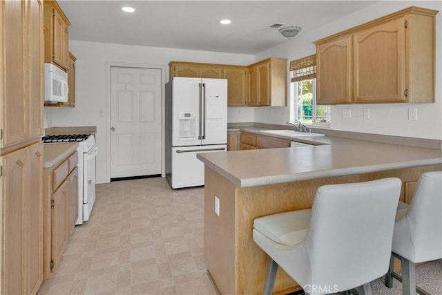 kitchen with light countertops, a sink, a peninsula, light floors, and white appliances