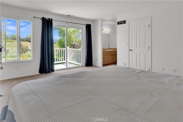 carpeted bedroom featuring access to outside, a sink, visible vents, and multiple windows