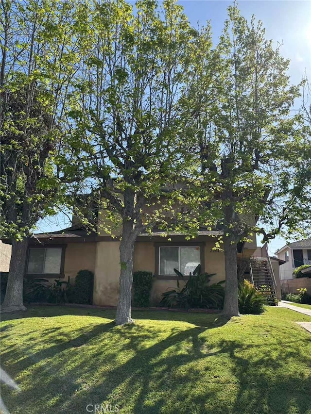 view of front of house featuring stairs, stucco siding, and a front lawn