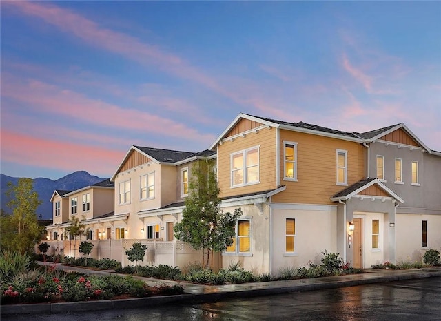 view of front facade featuring fence, stucco siding, board and batten siding, and a residential view