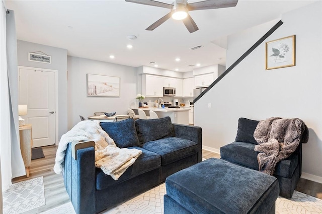 living area featuring light wood-style flooring, a ceiling fan, recessed lighting, and baseboards