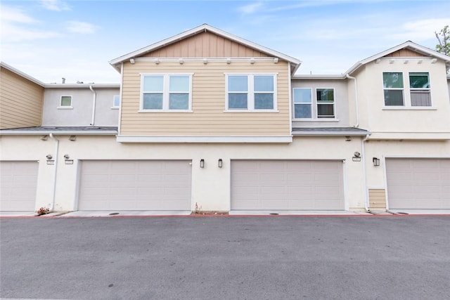 multi unit property featuring stucco siding, an attached garage, and board and batten siding