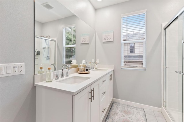 full bath with a stall shower, double vanity, baseboards, and tile patterned flooring