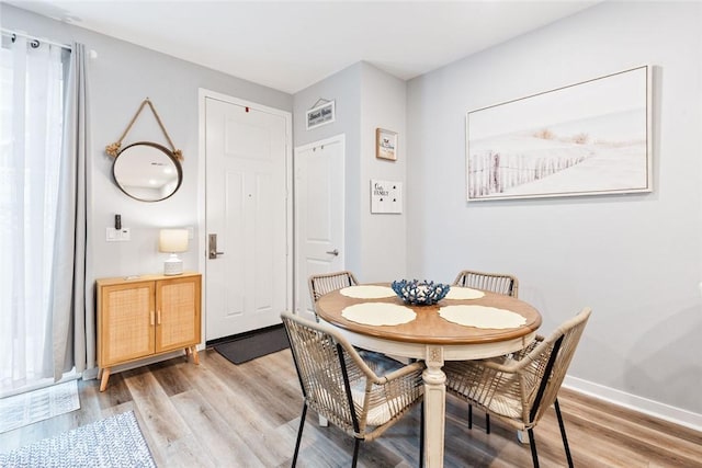 dining space featuring light wood finished floors and baseboards