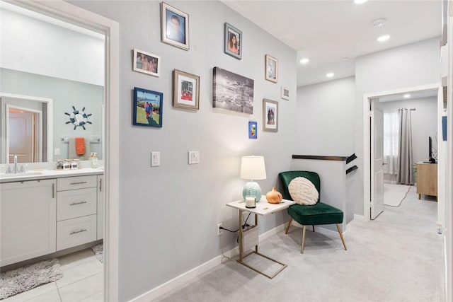 hallway with recessed lighting, a sink, baseboards, and light colored carpet