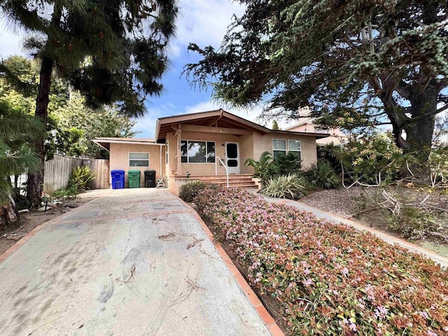 ranch-style house featuring fence, stucco siding, and concrete driveway