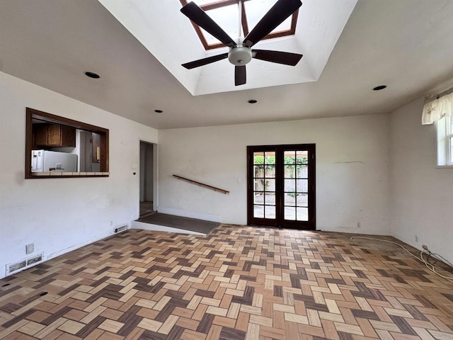 spare room with a ceiling fan, visible vents, and vaulted ceiling with skylight