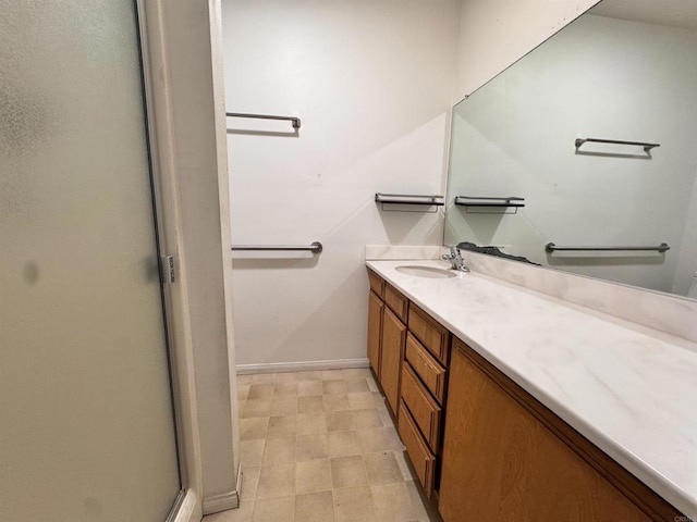 bathroom with a stall shower, baseboards, and vanity