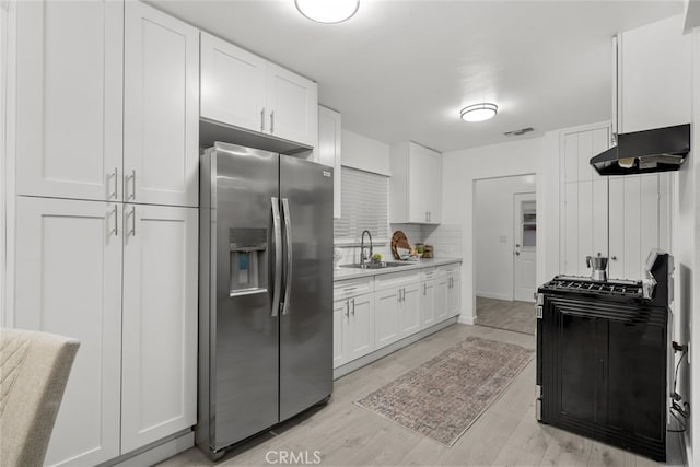 kitchen featuring white cabinets, a sink, under cabinet range hood, stainless steel refrigerator with ice dispenser, and visible vents