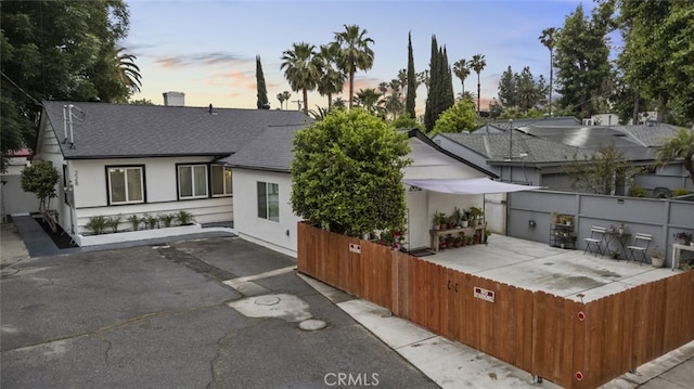 exterior space featuring a shingled roof, a patio area, stucco siding, and fence