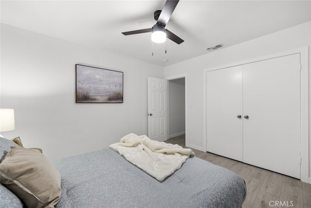 bedroom featuring a closet, a ceiling fan, visible vents, and light wood-style floors
