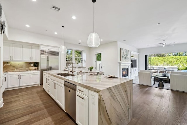 kitchen featuring visible vents, appliances with stainless steel finishes, a sink, open floor plan, and a glass covered fireplace