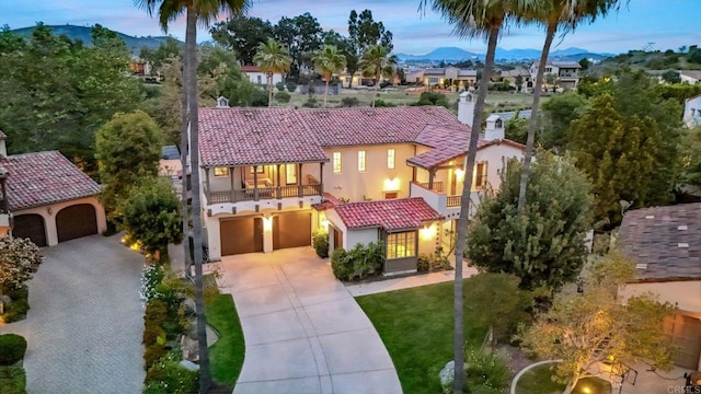 mediterranean / spanish house featuring a tile roof, a mountain view, a balcony, concrete driveway, and stucco siding