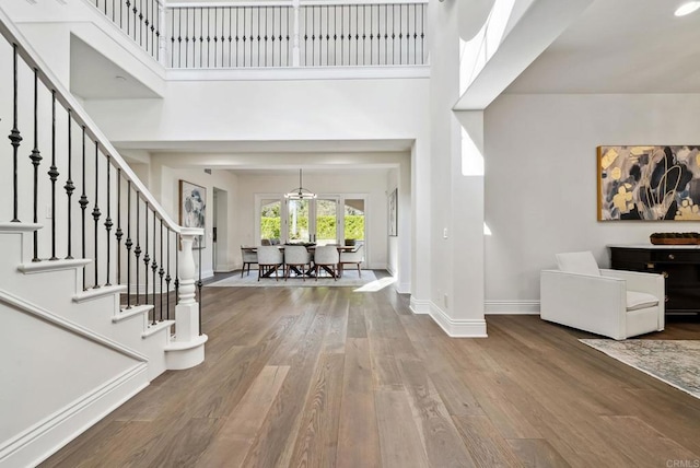 entryway featuring wood finished floors, baseboards, a high ceiling, stairway, and french doors