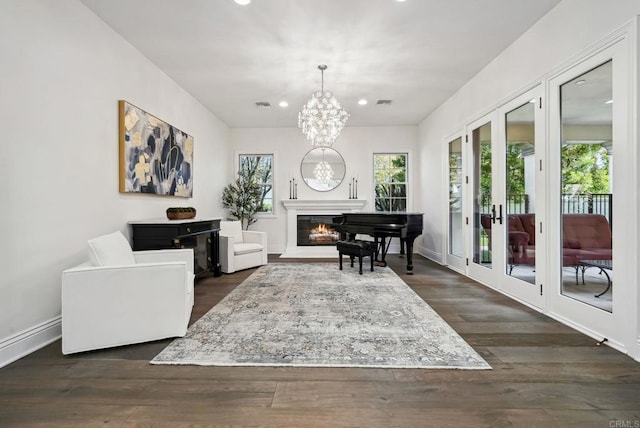 sitting room with a notable chandelier, a glass covered fireplace, french doors, recessed lighting, and dark wood-type flooring