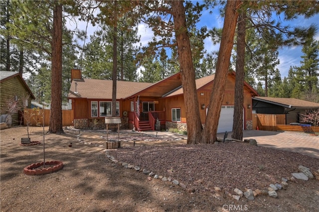 back of property with fence, an attached garage, driveway, and a chimney