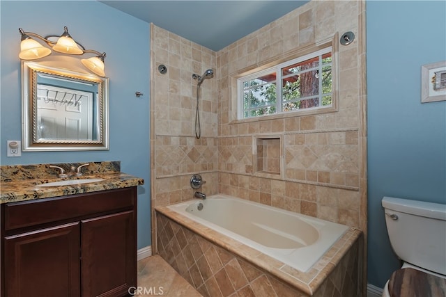 bathroom with tile patterned flooring, vanity, baseboards, toilet, and tiled shower / bath combo