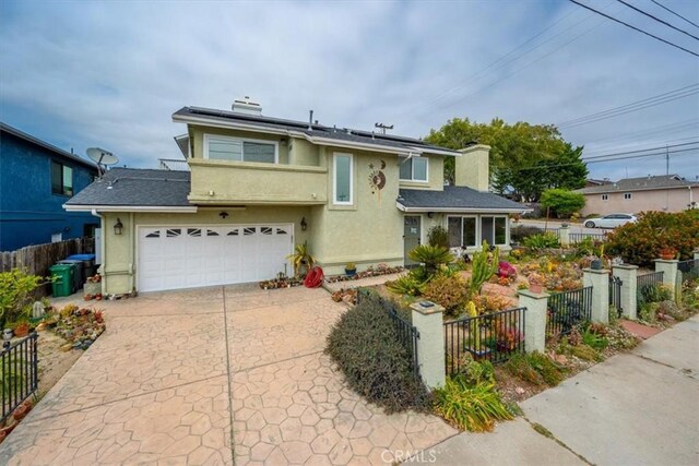 1585 Saratoga Ave, Grover Beach, CA 93433 - view of front of home featuring a chimney, concrete driveway, an attached garage, solar panels, and stucco siding