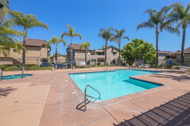 community pool featuring a patio area, fence, and a residential view