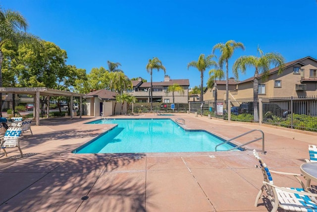 pool with a patio, fence, and a residential view