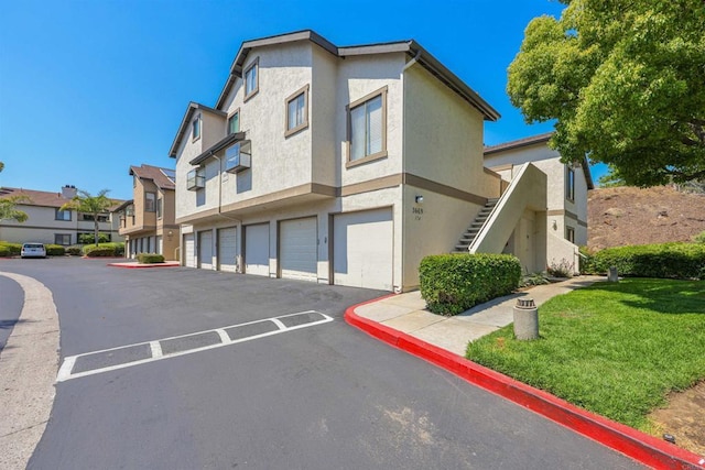 view of property with stairs, an attached garage, and a residential view