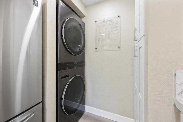 laundry room with stacked washing maching and dryer, laundry area, and wood finished floors