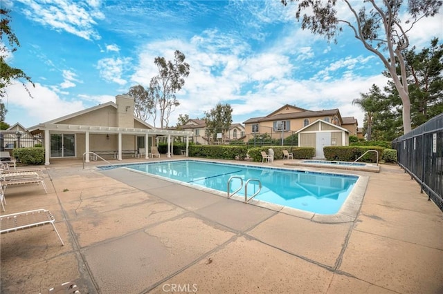 pool featuring a hot tub, fence, an outdoor structure, a patio, and a pergola