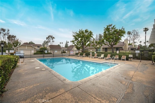 community pool featuring fence, a residential view, and a patio area