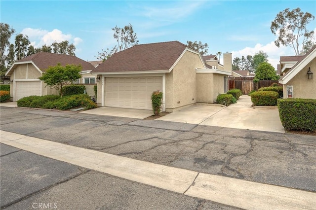 view of front of house featuring an attached garage, fence, a chimney, and stucco siding