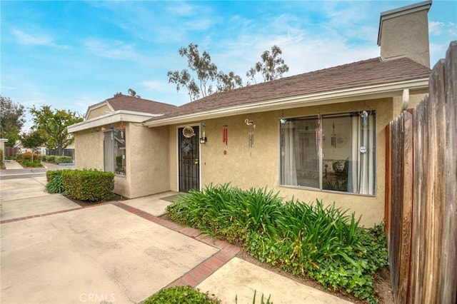 view of front of property featuring fence, a patio area, and stucco siding