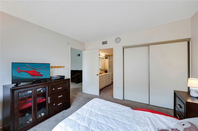 carpeted bedroom featuring ensuite bathroom, a closet, and visible vents