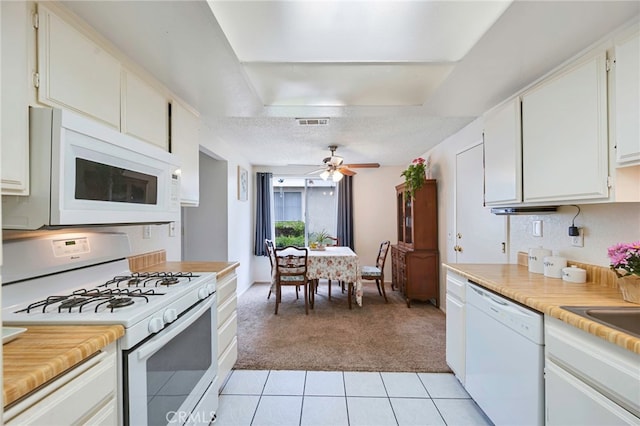 kitchen with visible vents, light colored carpet, light countertops, white cabinets, and white appliances