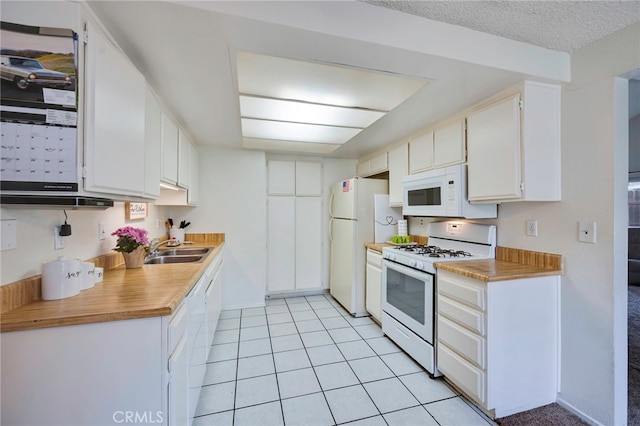 kitchen with light tile patterned flooring, a sink, white appliances, light countertops, and white cabinetry