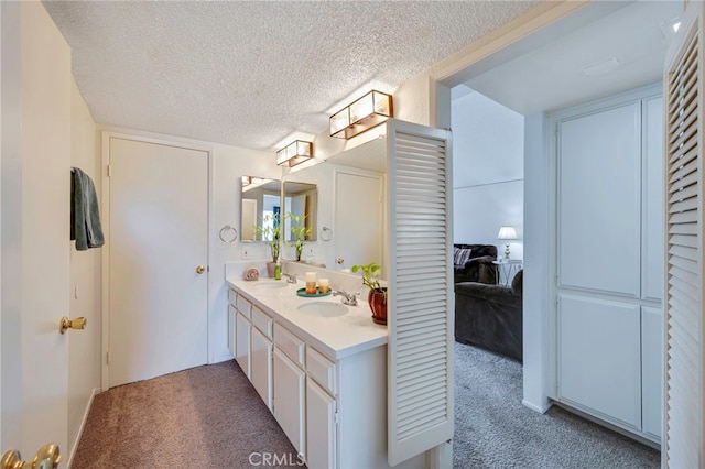ensuite bathroom with a sink, double vanity, ensuite bath, and a textured ceiling