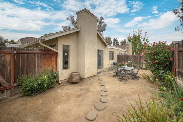rear view of house with a chimney, a fenced backyard, a patio area, and stucco siding