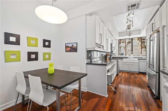 kitchen featuring visible vents, dark wood finished floors, high quality fridge, dishwasher, and a sink