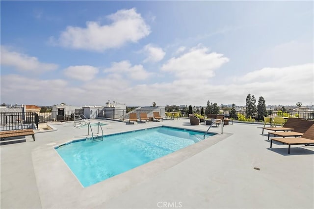 pool with a patio area and fence